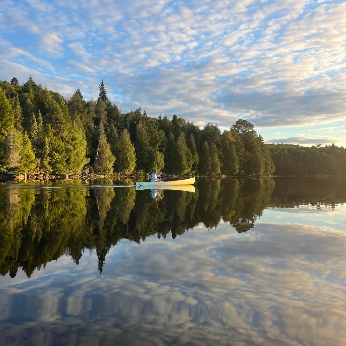 Canoeing through glassy water at sunset in Algonquin Park.