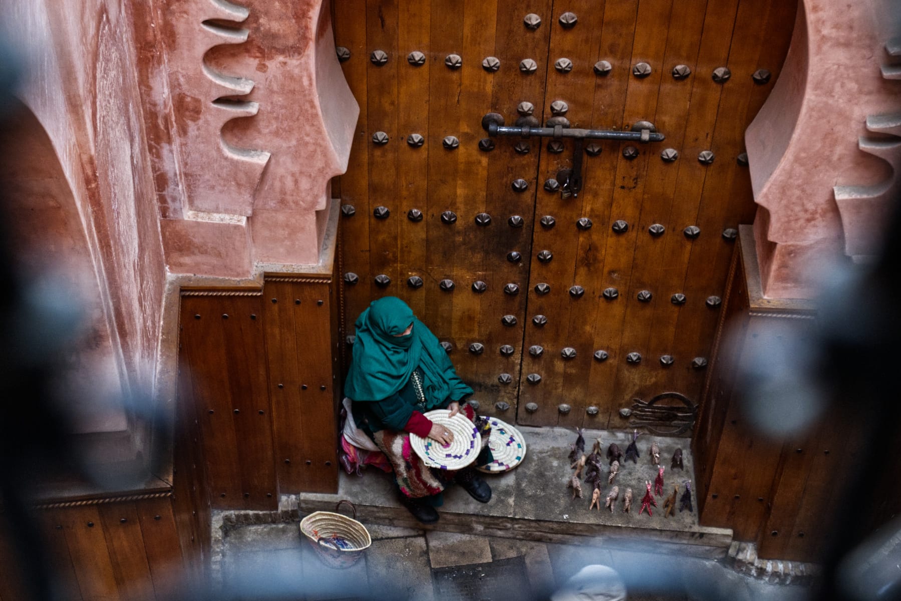 A woman selling trinkets in the Medina of Marrakech. Doorways are a central place of commerce, discussion, transport, and culture.